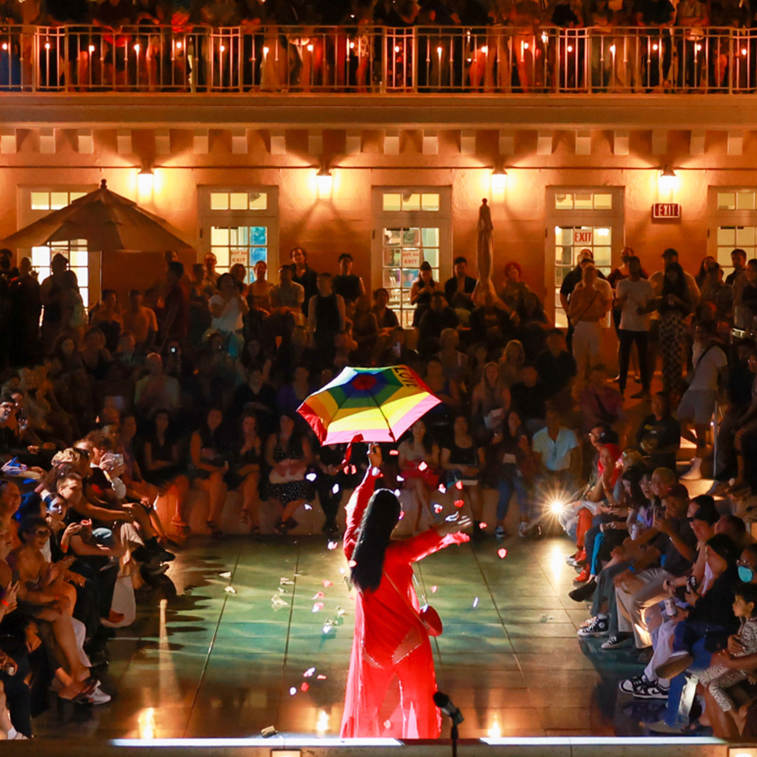 Performers and audience in outdoor space at night.
