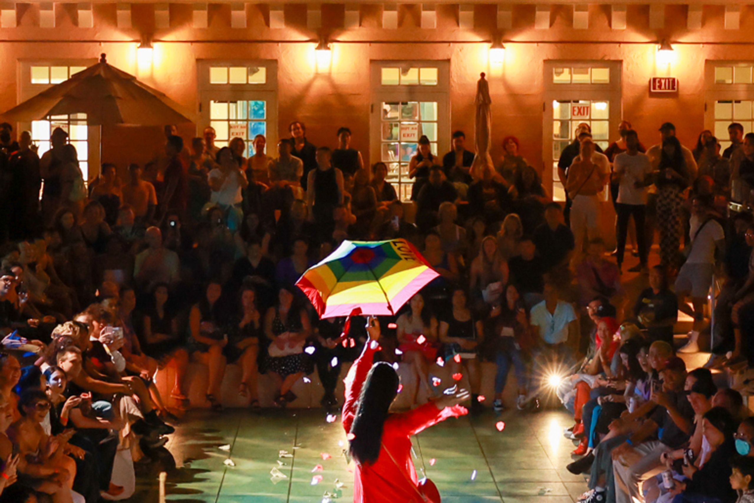Performers and audience in outdoor space at night.