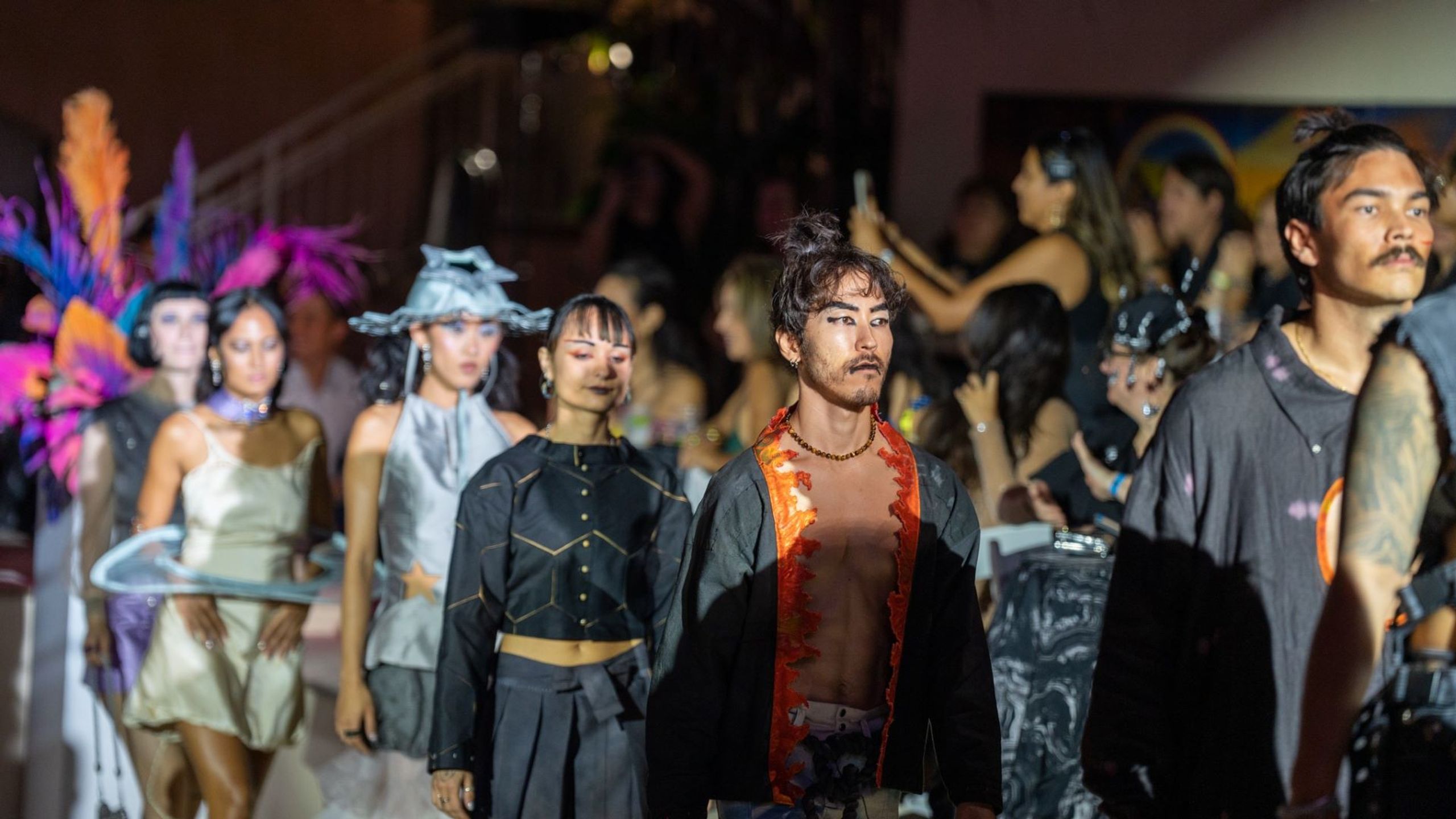 View of fashion show with models walking past an audience.