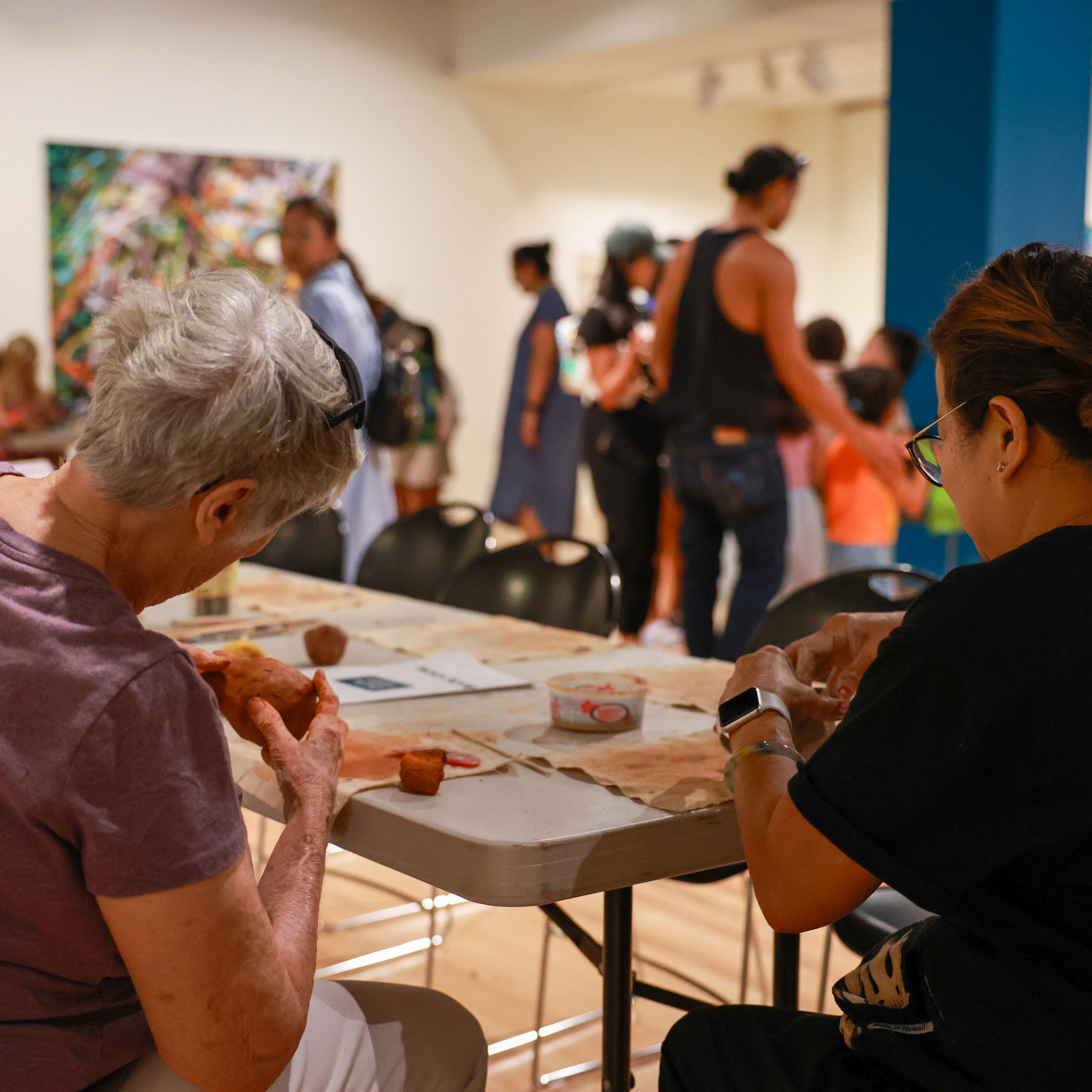 People sitting at a table and shaping clay into bowls.