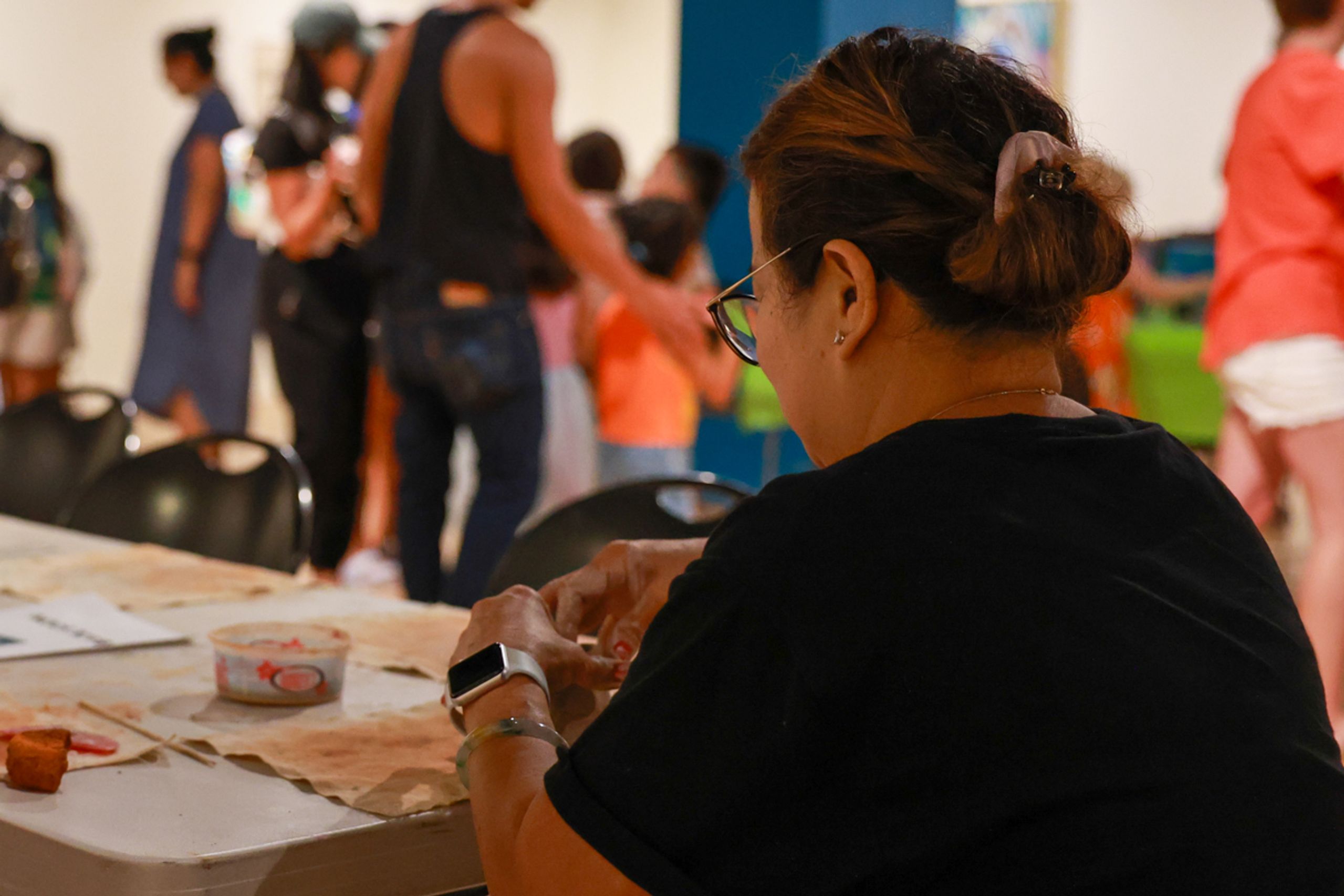 People sitting at a table and shaping clay into bowls.