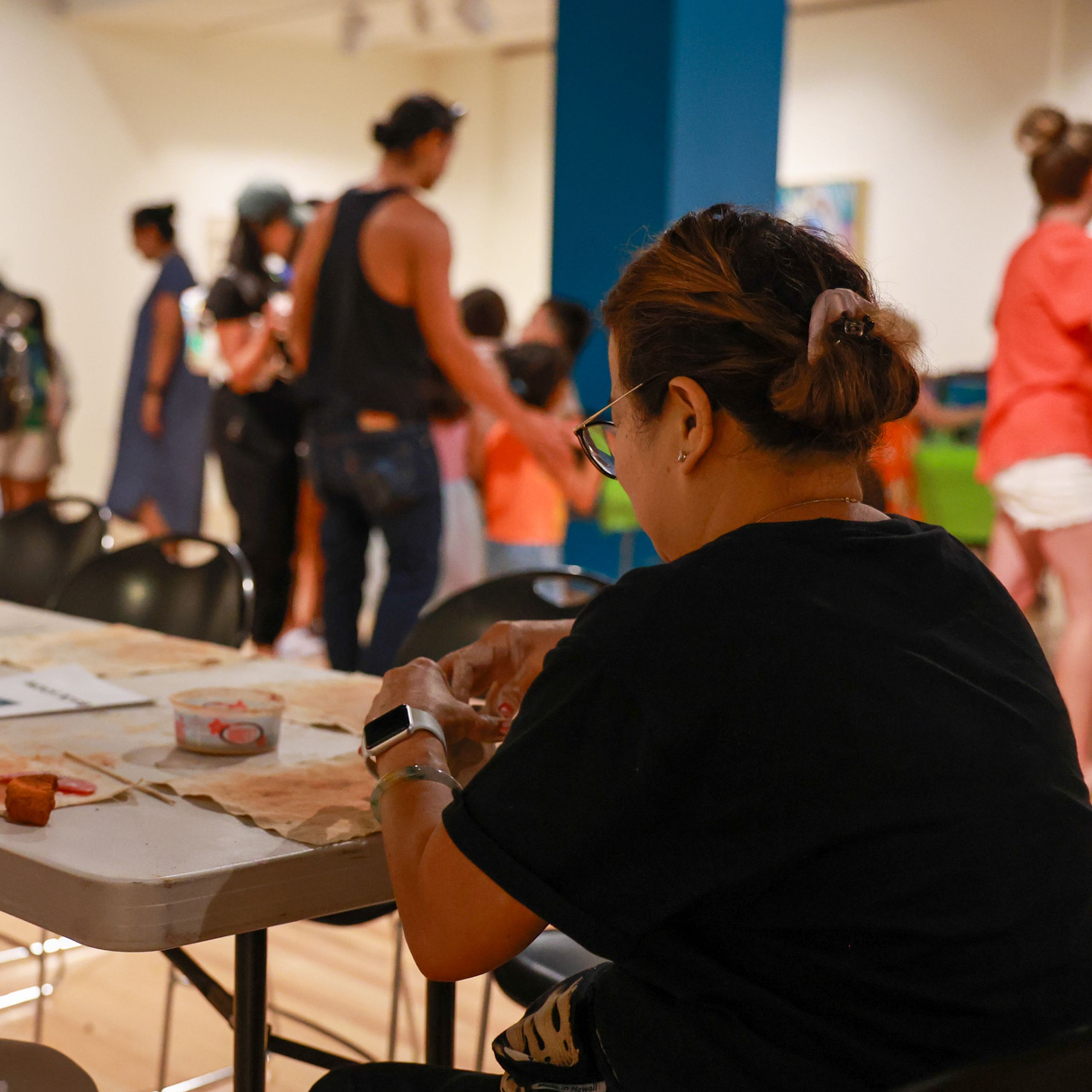 People sitting at a table and shaping clay into bowls.