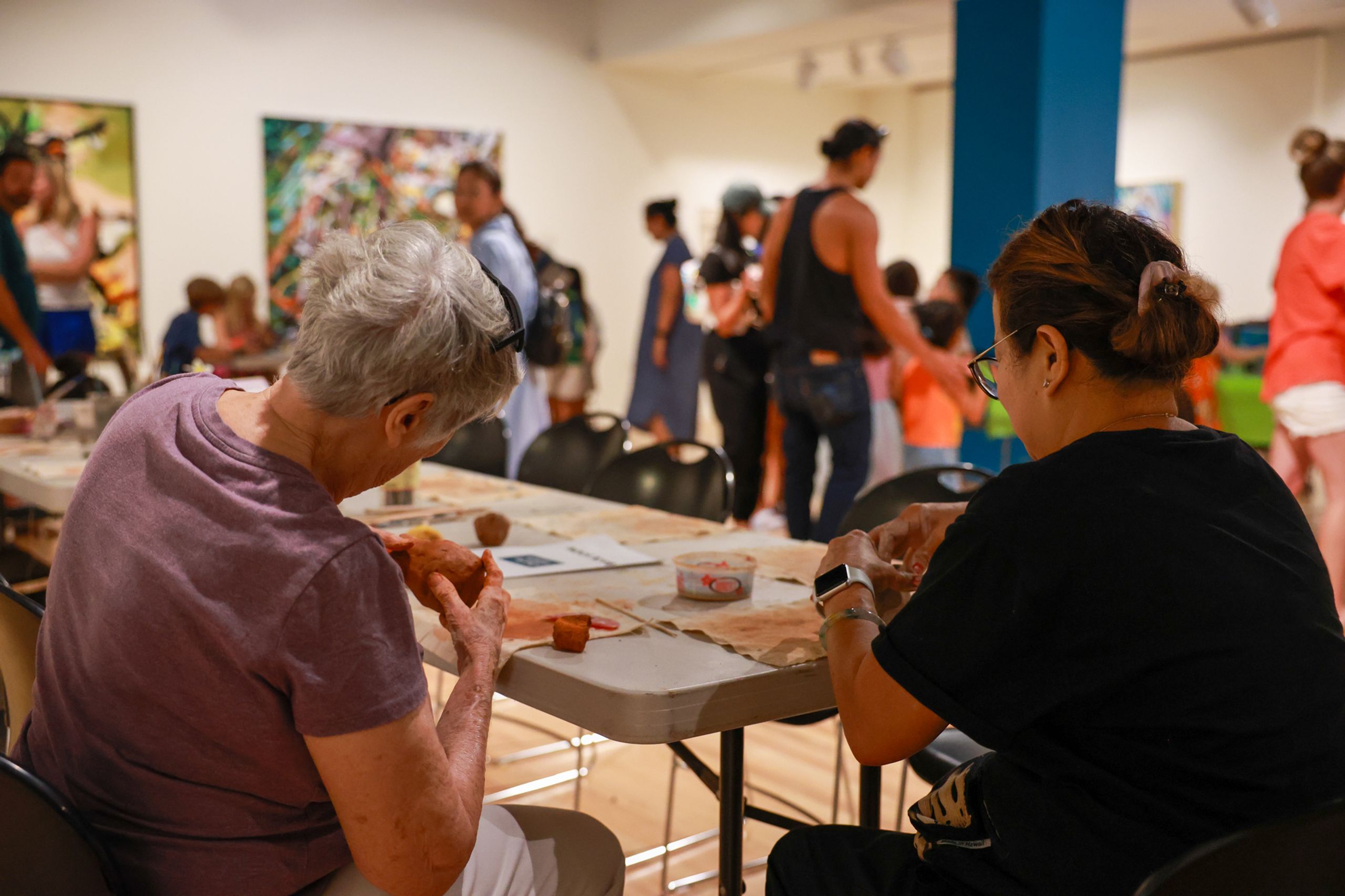 People sitting at a table and shaping clay into bowls.