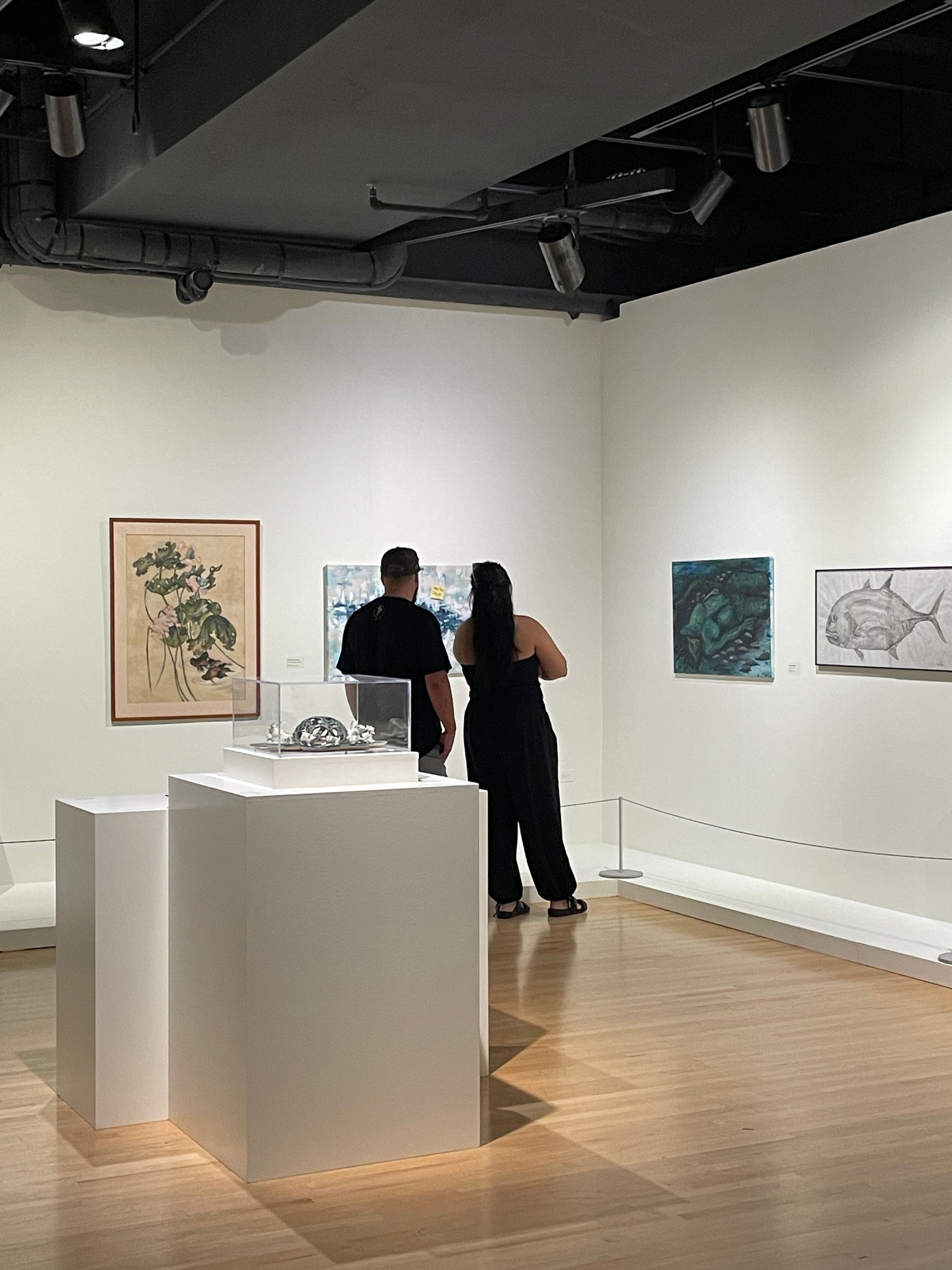 Two people observe artwork in a gallery