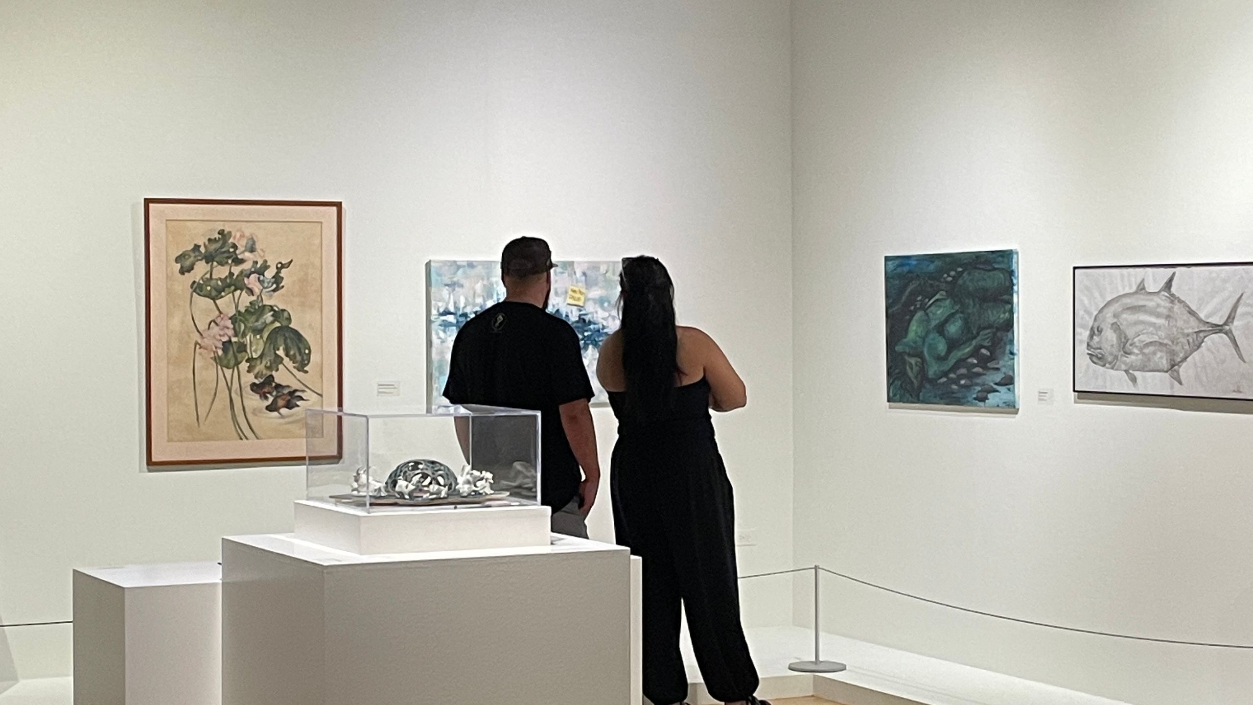 Two people observe artwork in a gallery