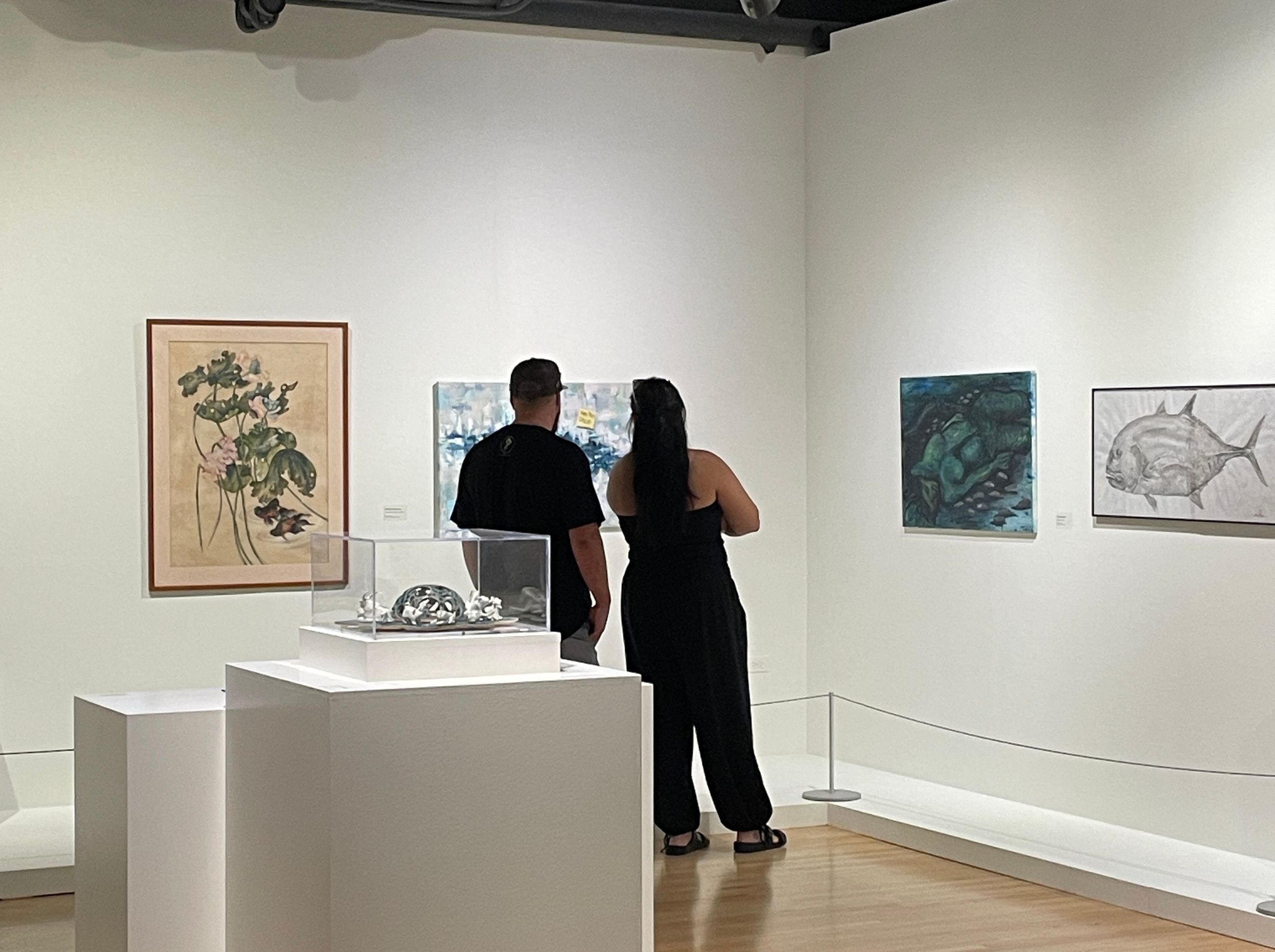 Two people observe artwork in a gallery