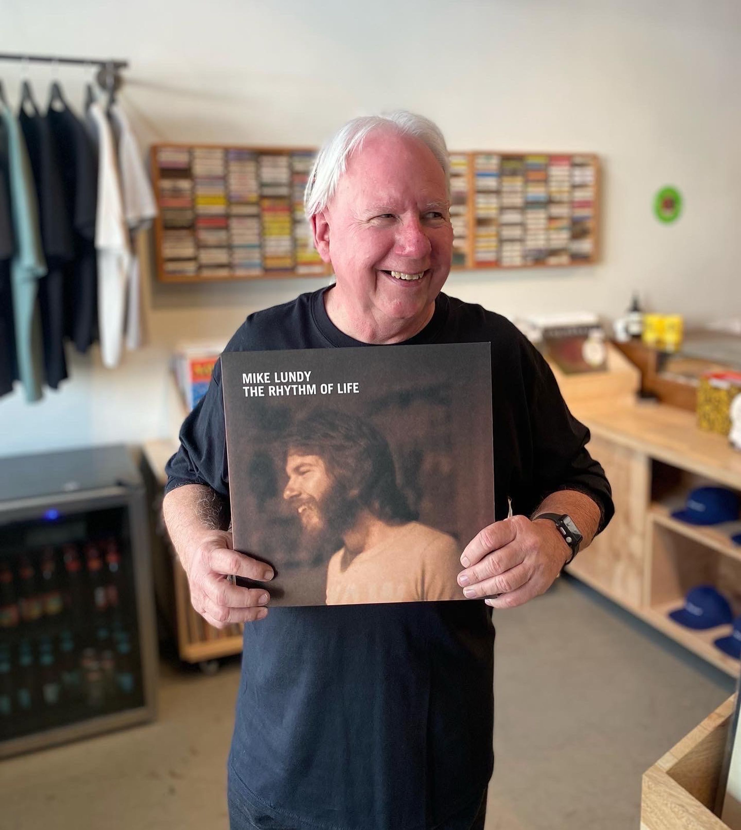 Mike Lundy holding a copy of his vinyl record "The Rhythm of Life"