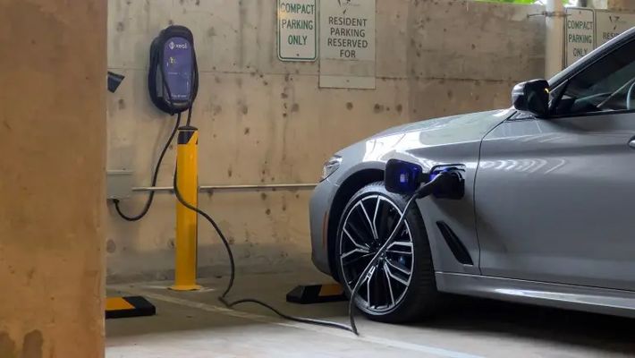 an electric car is being charged at a charging station in a parking garage .