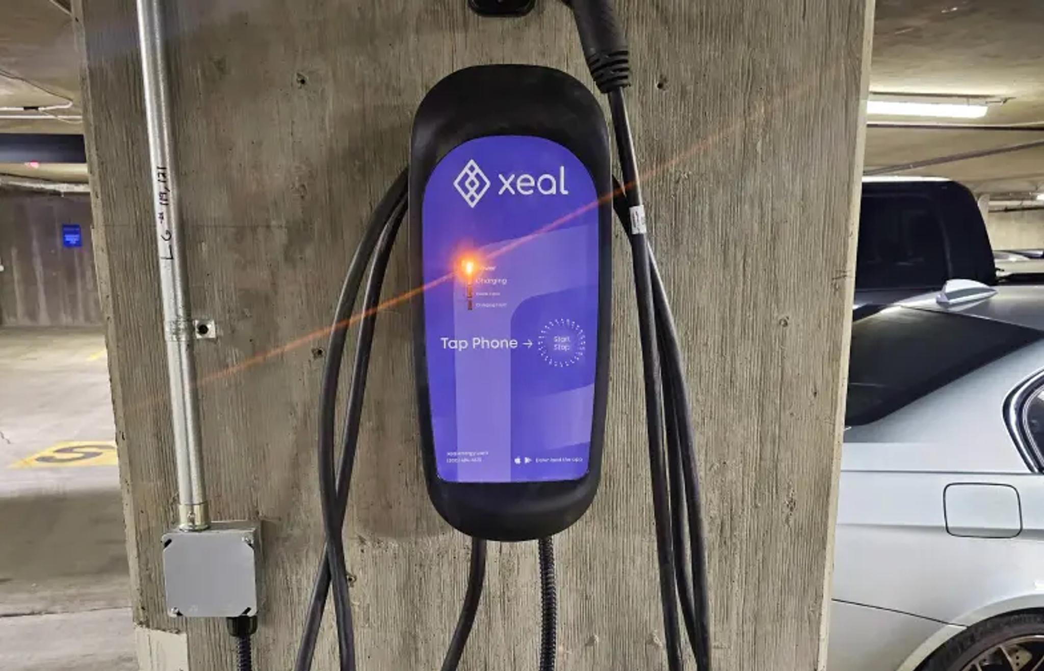 a car is being charged at a xeal charging station in a parking garage .