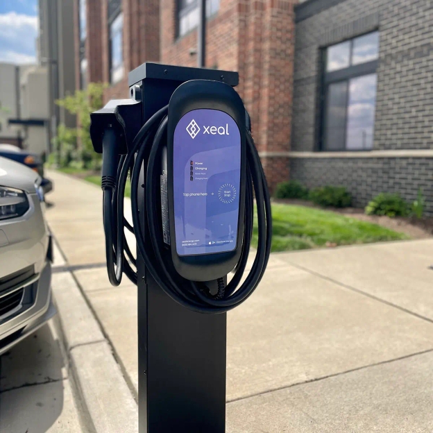 a car is being charged at a charging station on the side of the road .
