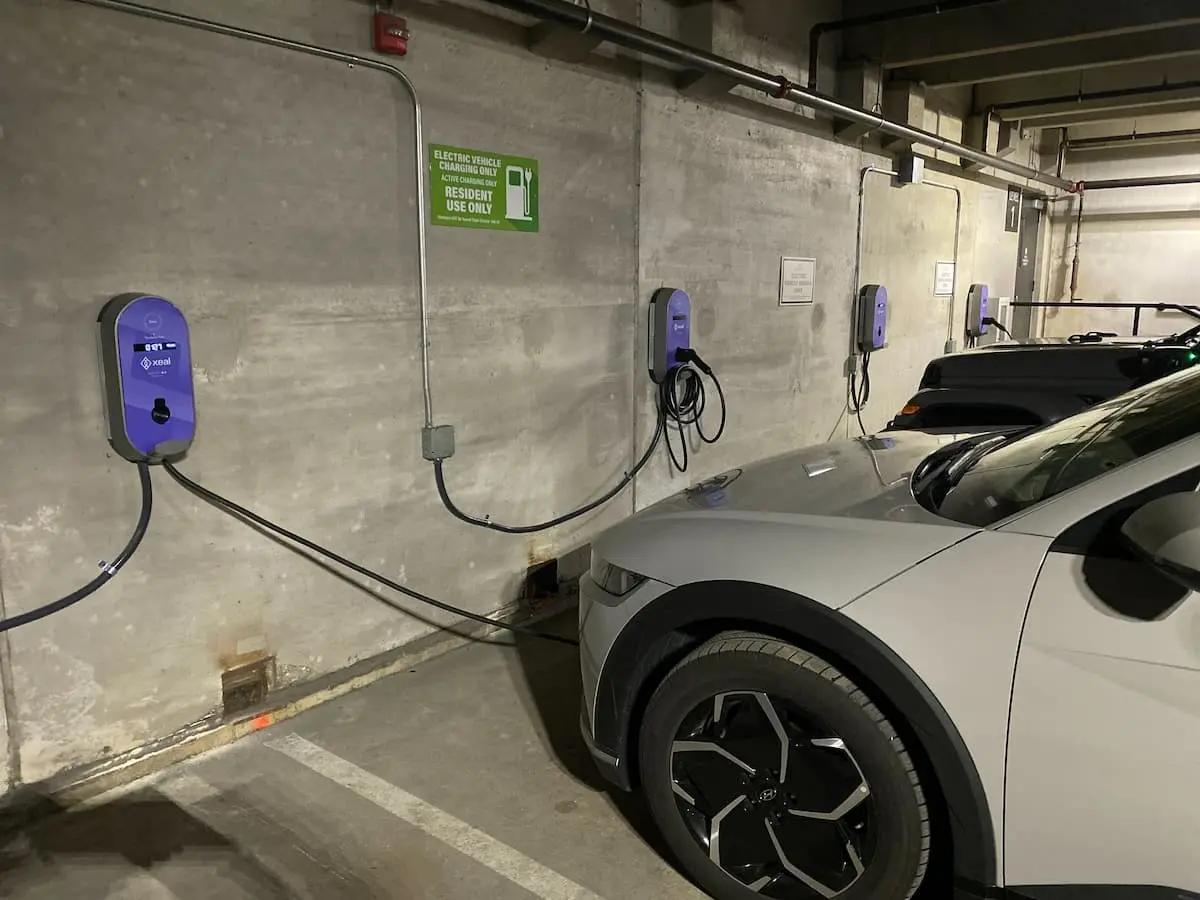 two electric cars are being charged at charging stations in a parking garage .