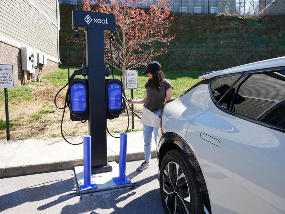 a woman is charging her electric car at a charging station .