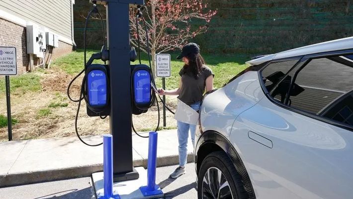 a woman is charging her electric car at a charging station .