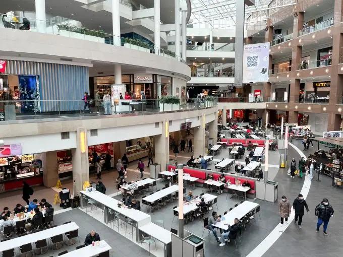 a large shopping mall filled with lots of tables and chairs .
