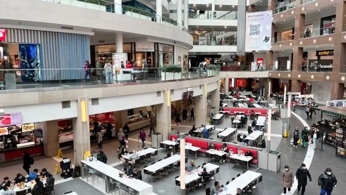a large shopping mall filled with lots of tables and chairs .