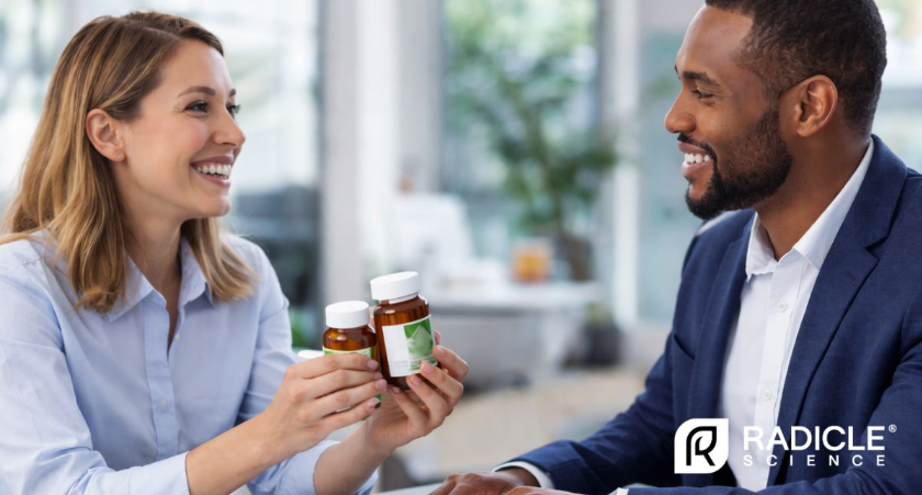 Woman holding two pill bottles showing them to man next to her