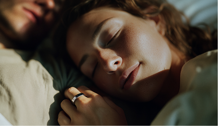overhead view of a couple sleeping in a bed woman is wearing smart ring