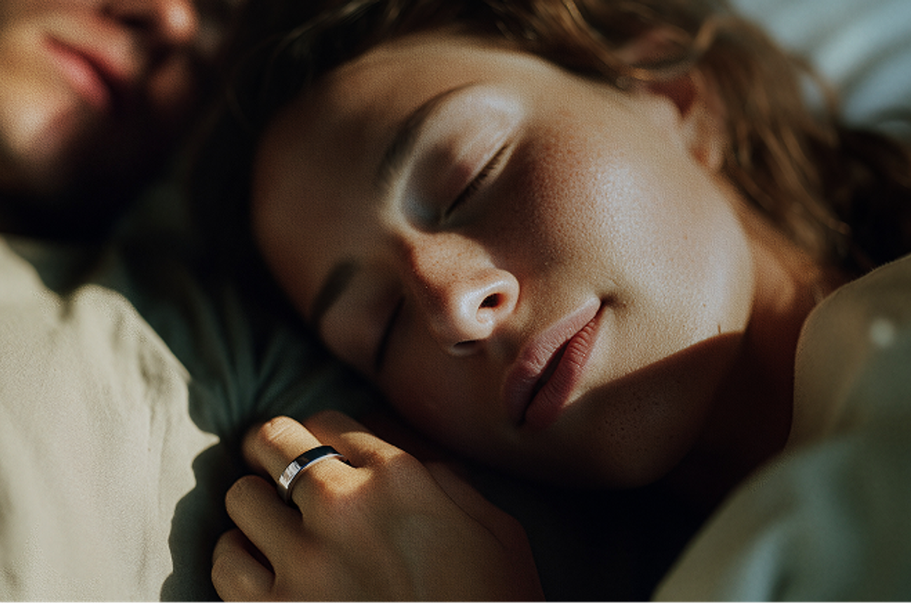 overhead view of a couple sleeping in a bed woman is wearing smart ring