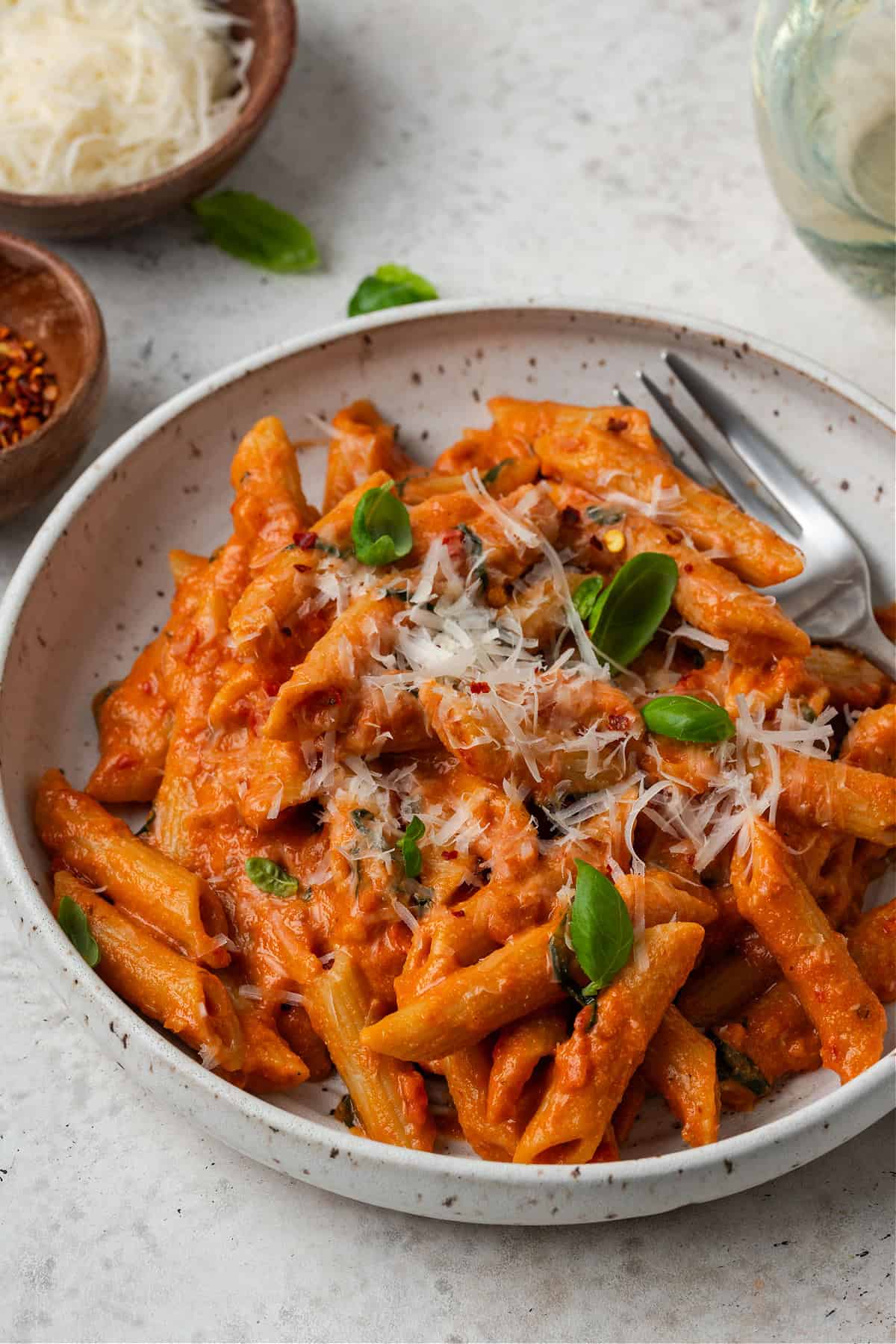 A bowl of vegan creamy tomato pasta topped with vegan Parmesan. 