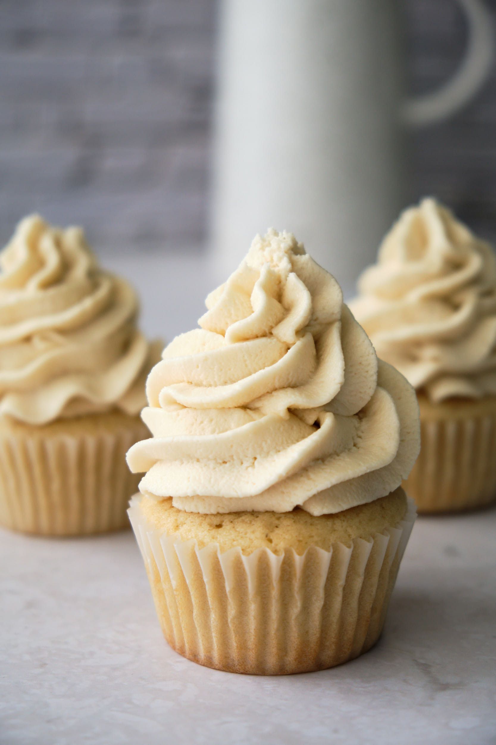 Three vanilla cupcakes topped with vegan buttercream frosting.