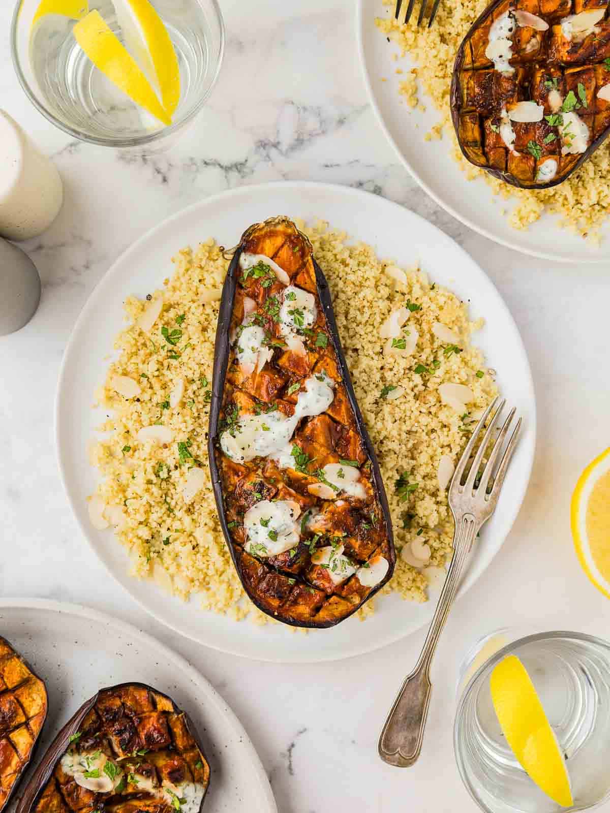 Three plates of harissa eggplant on a bed of couscous.
