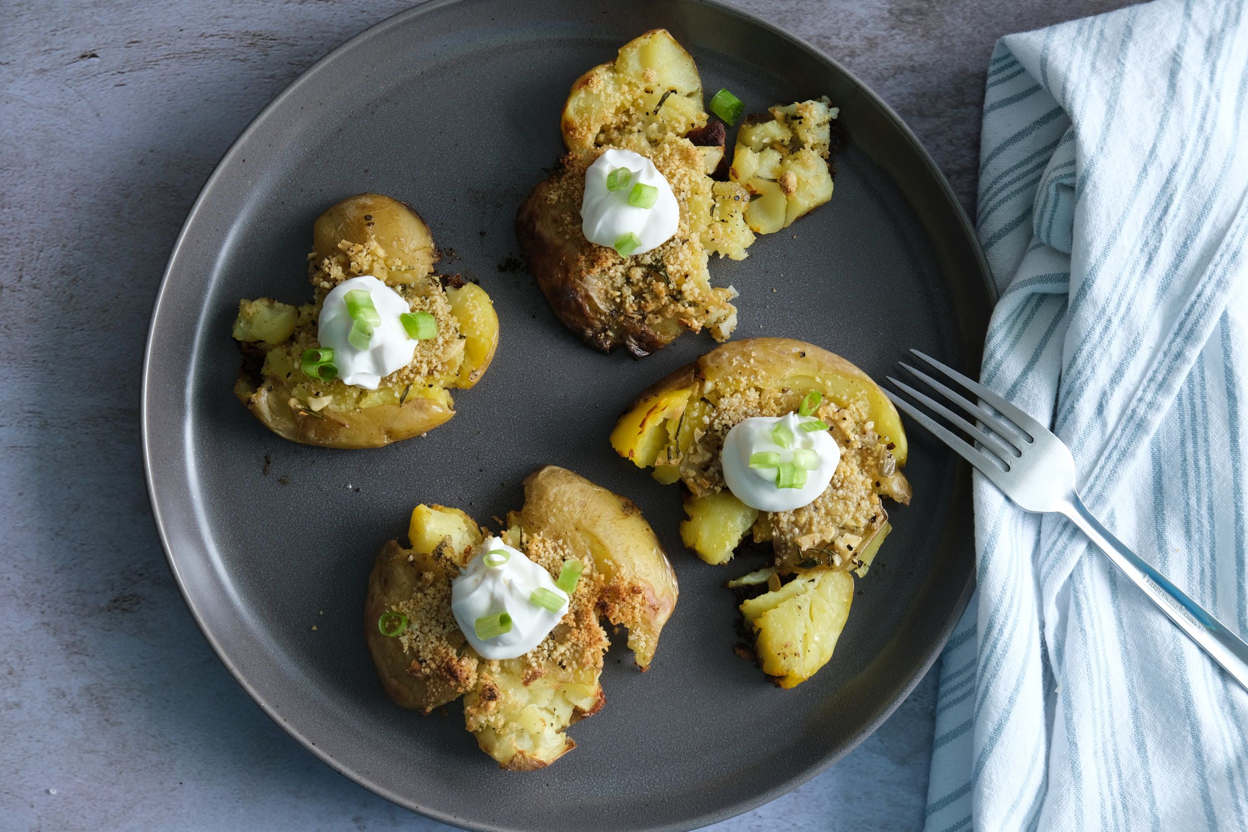 top down view of smashed potatoes with sour cream and green onions