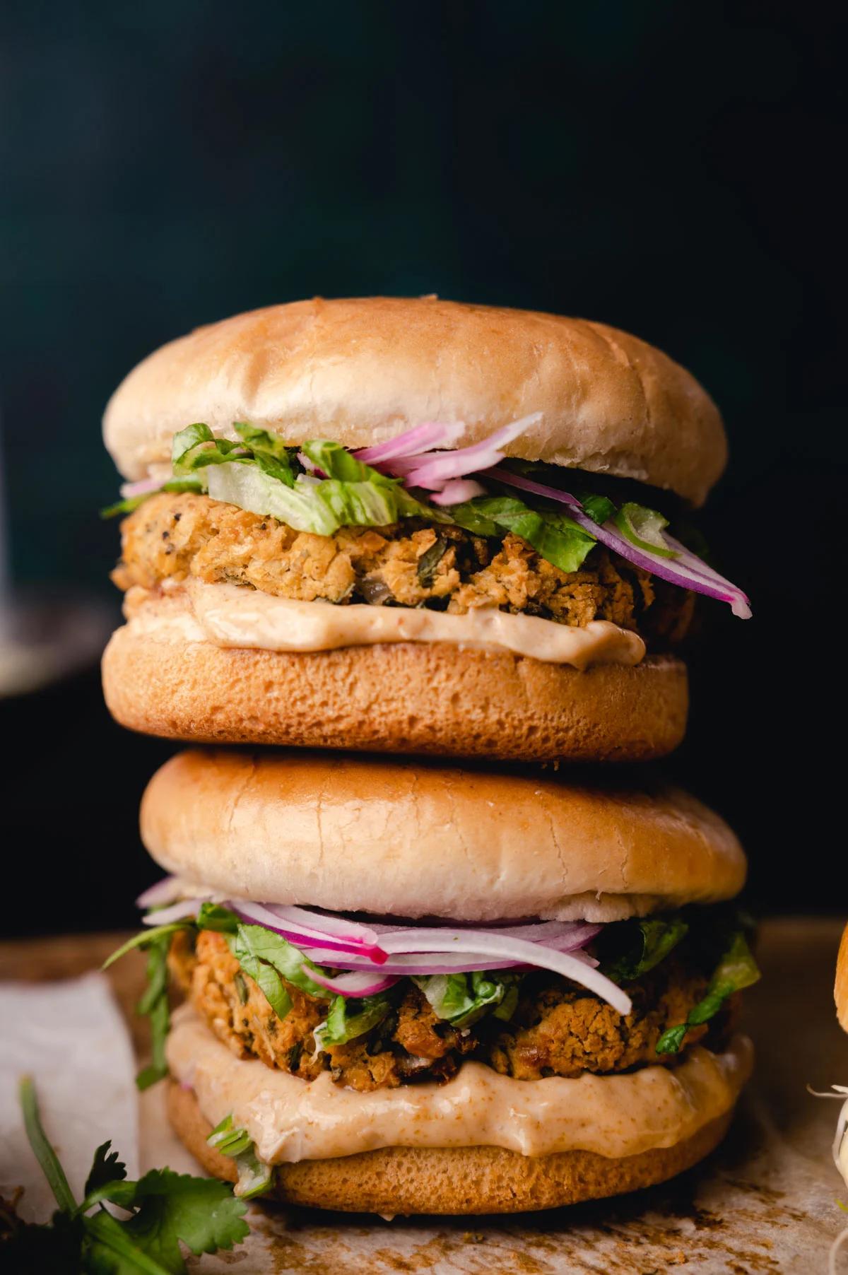 Two chickpea burgers stacked on a table. 