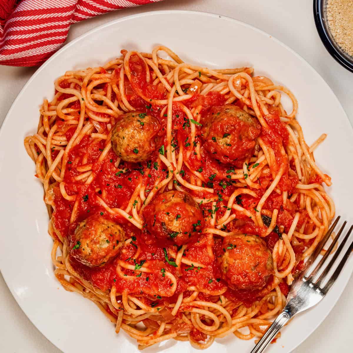A plate of spaghetti topped with marinara sauce and vegan meatballs. 