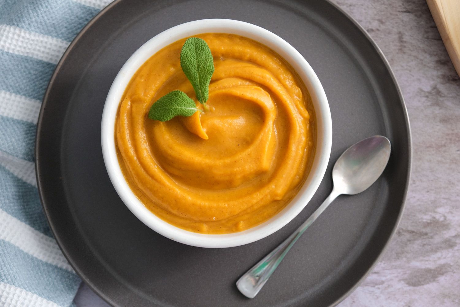 mashed-butternut-squash-in-bowl-with-sage-leaves-on-plate