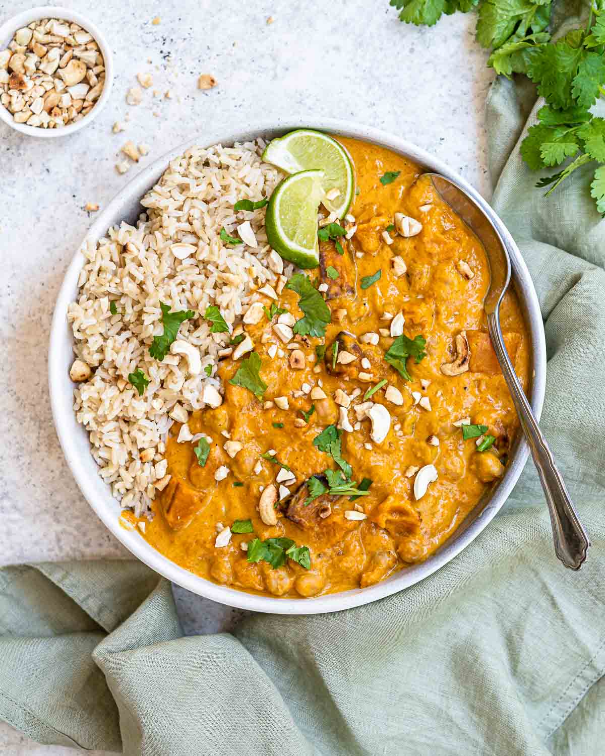 Butternut squash curry in a bowl with rice, cilantro, and lime slices. 