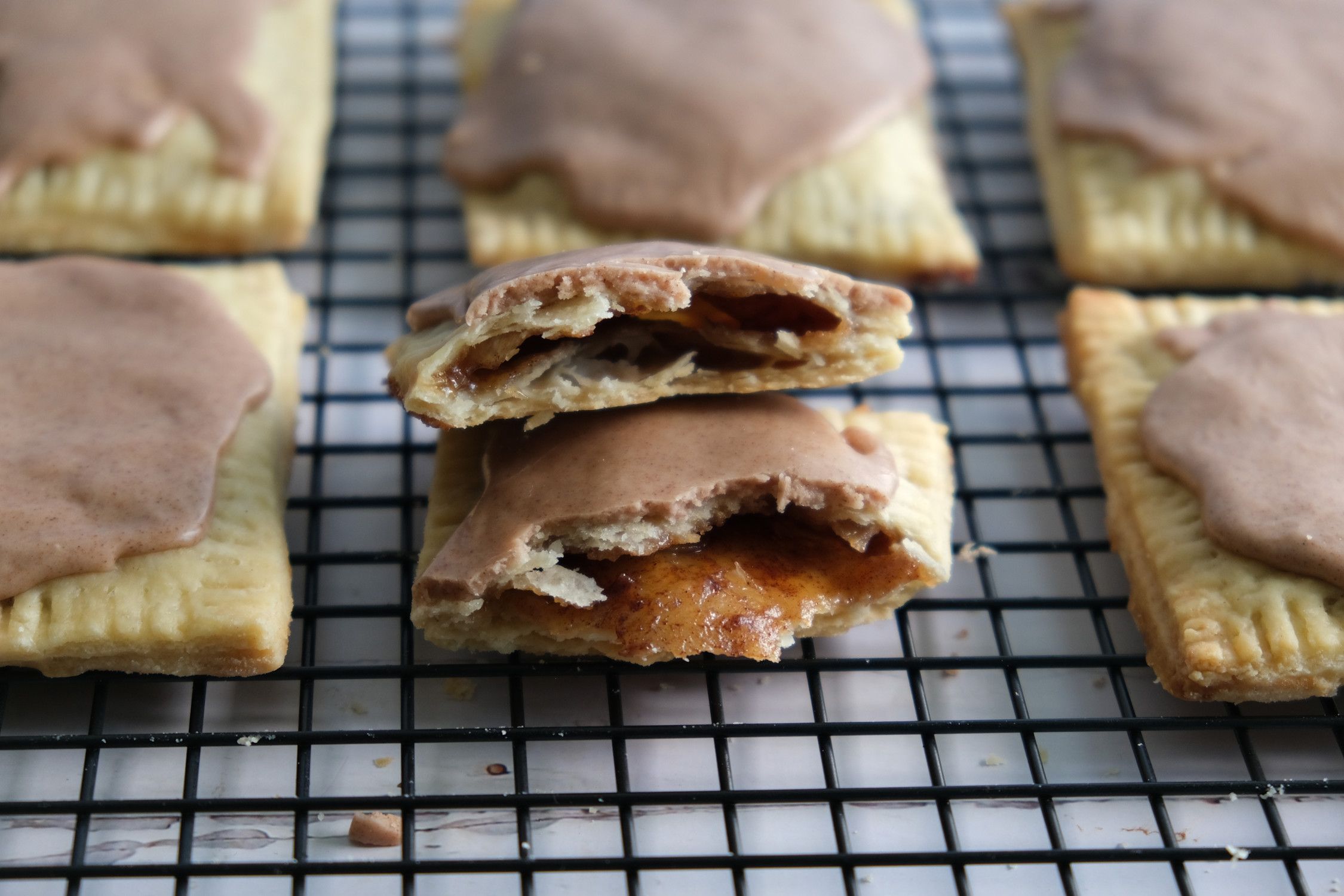 Brown sugar and cinnamon pop tarts on a cooling rack, with one broken in half, showing the inside.