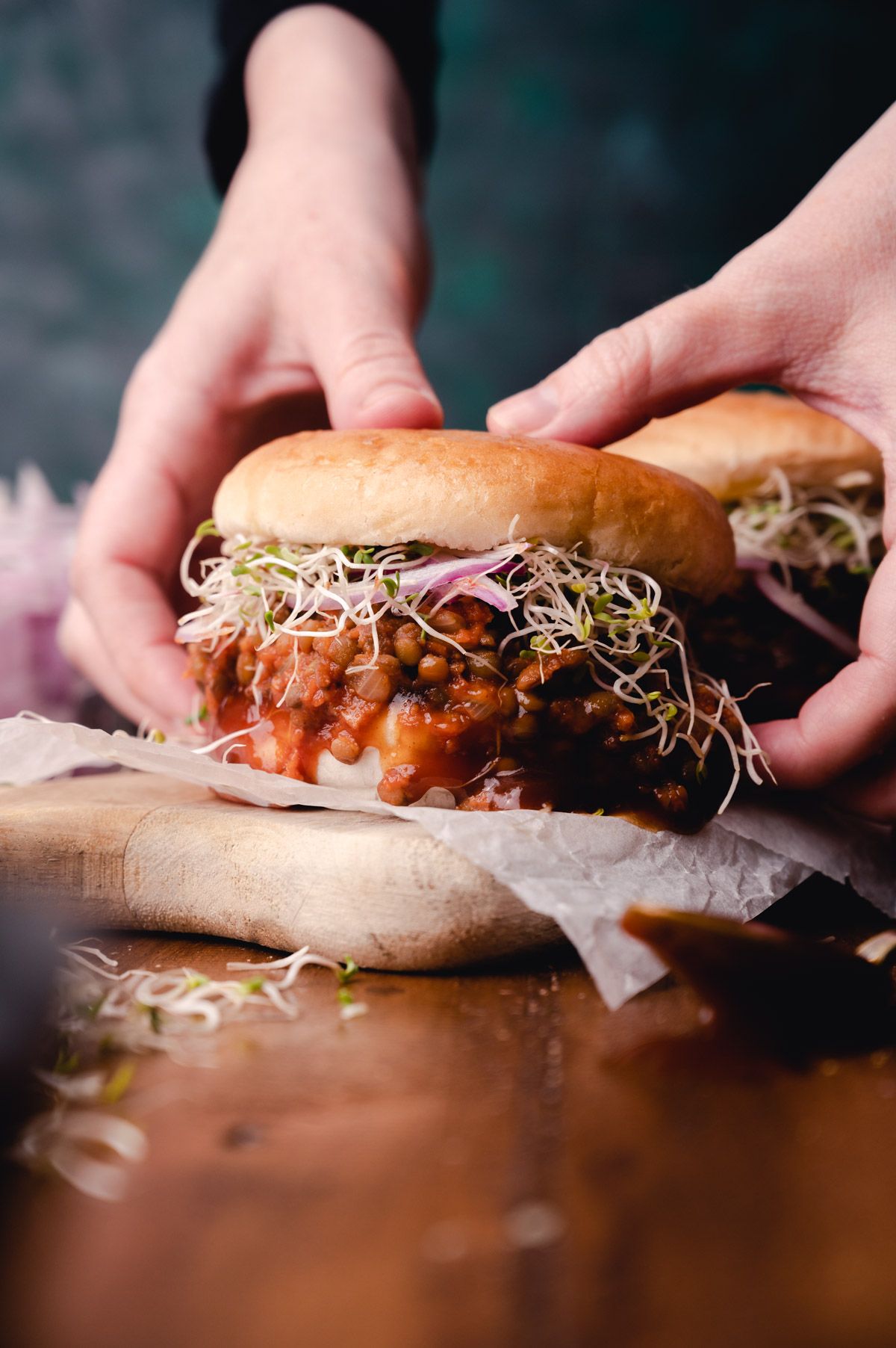 A pair of hands holding a vegan lentil sloppy Joe.