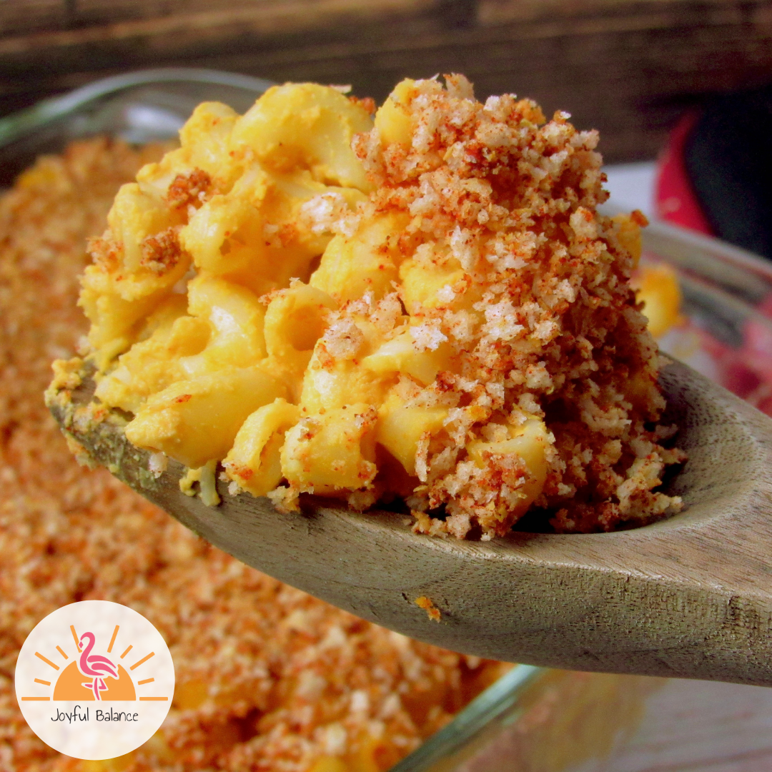 Vegan Butternut Squash Mac and Cheese on a wooden spoon in front of a casserole dish.