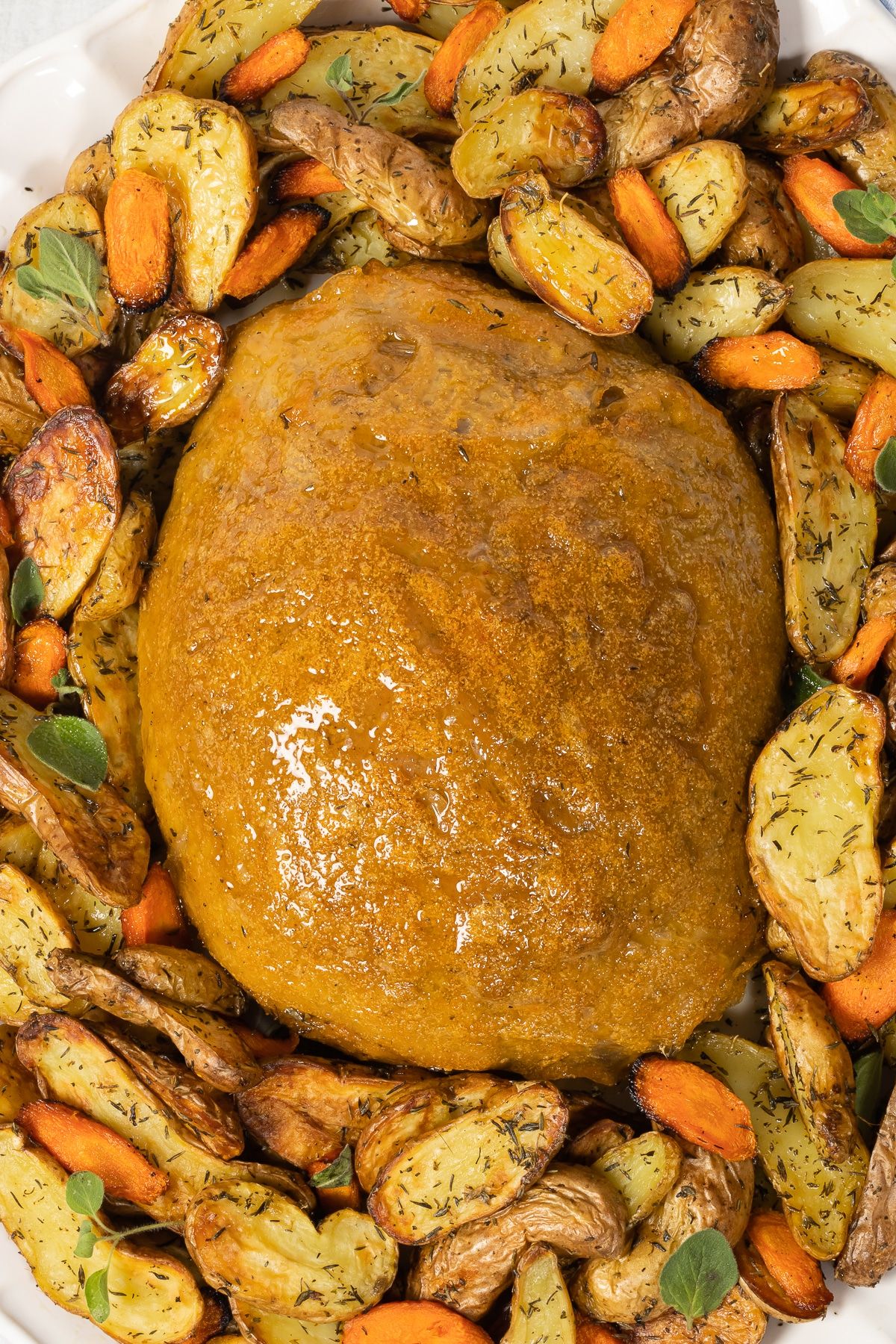 Vegan seitan turkey surrounded by roasted vegetables.