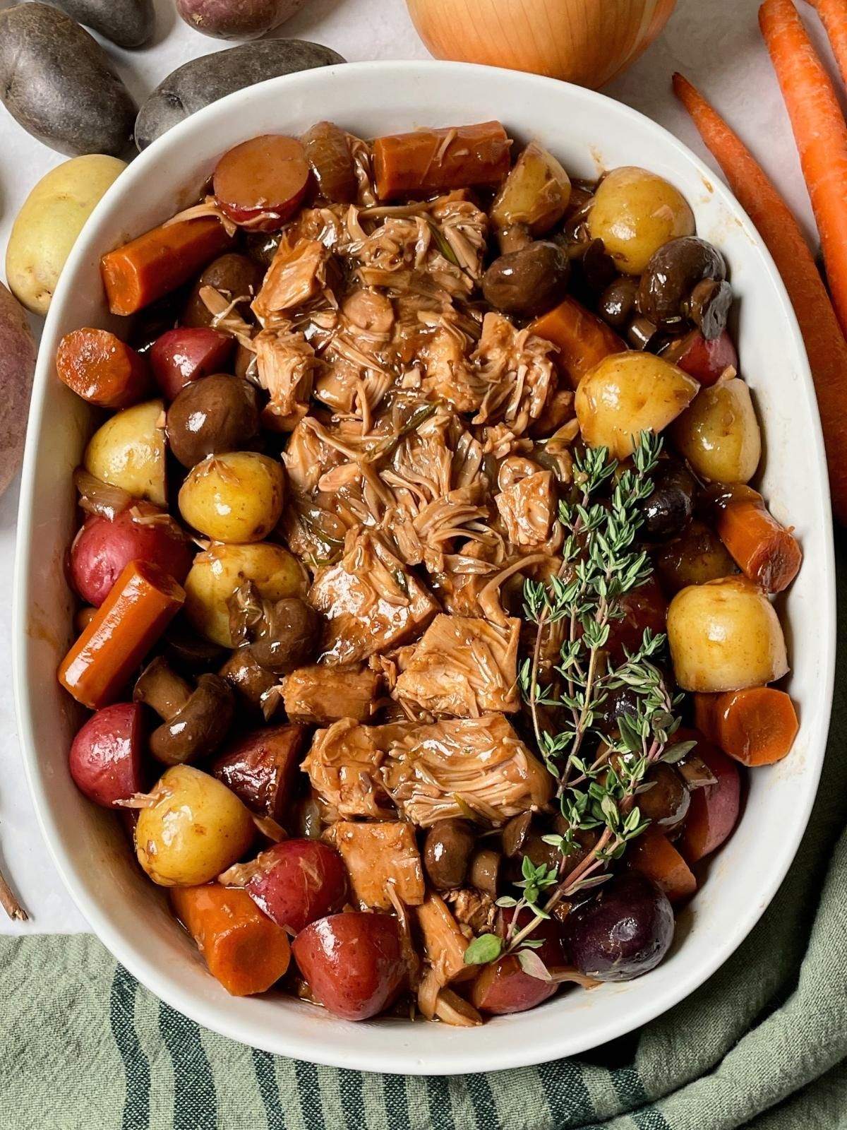 Vegan pot roast in a casserole dish, surrounded by vegetables. 