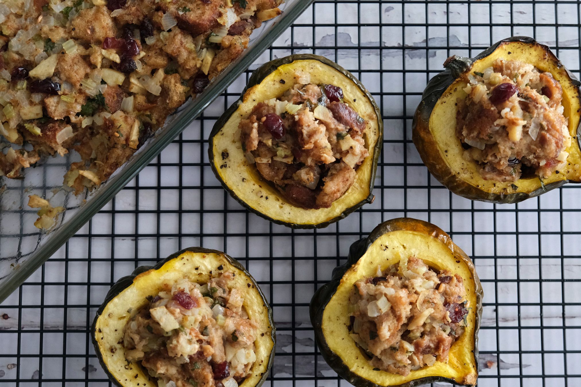 Cranberry apple vegan stuffing in acorn squash bowls with a dish of stuffing to the side