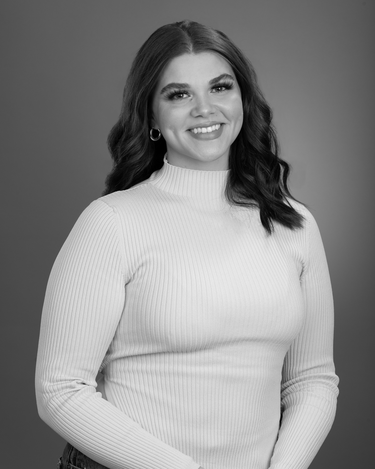 A black and white studio portrait of a smiling woman