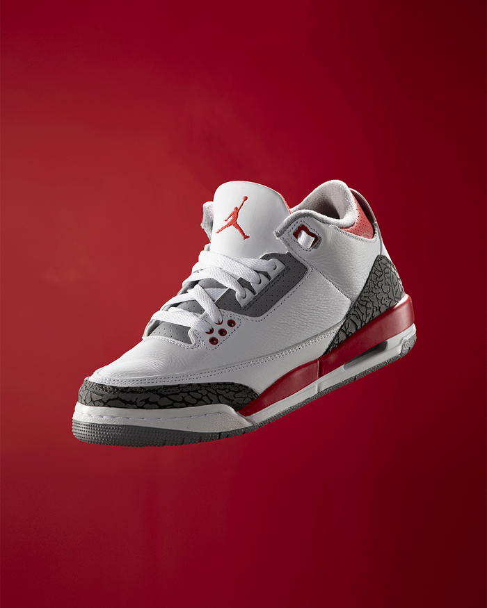 A red and white basketball sneaker against a deep red background