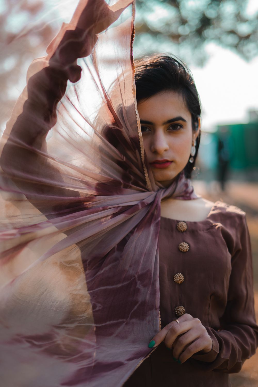 A woman in a rose-coloured dupatta catching the light outdoors