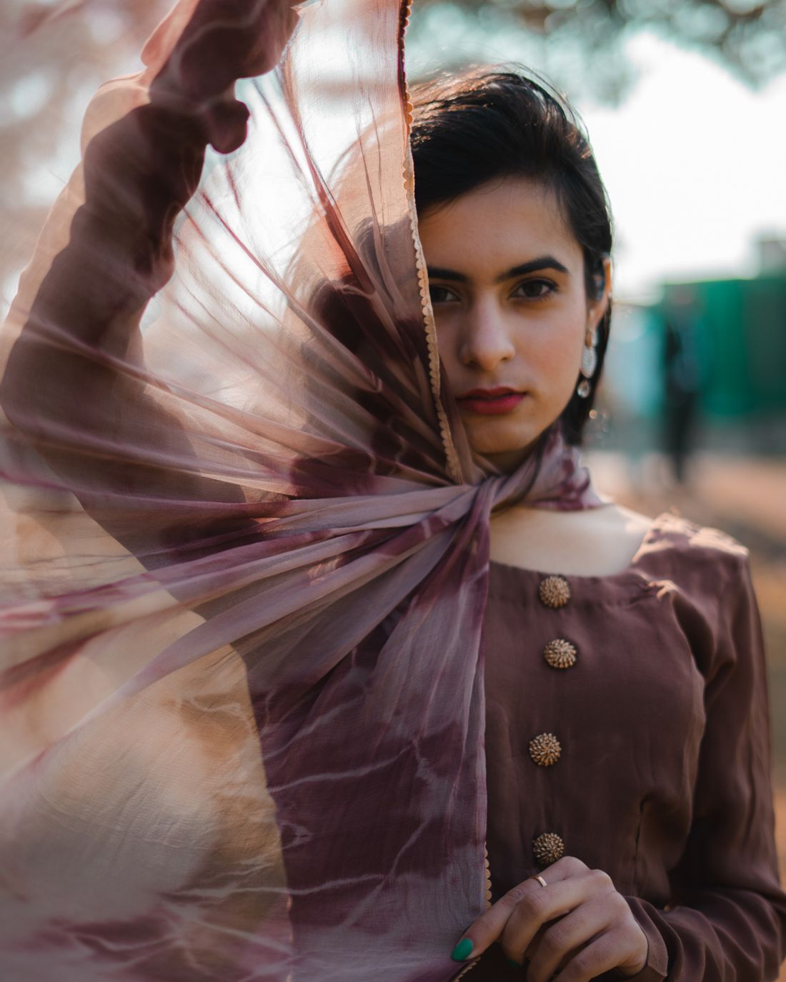 A woman in a rose-coloured dupatta catching the light outdoors