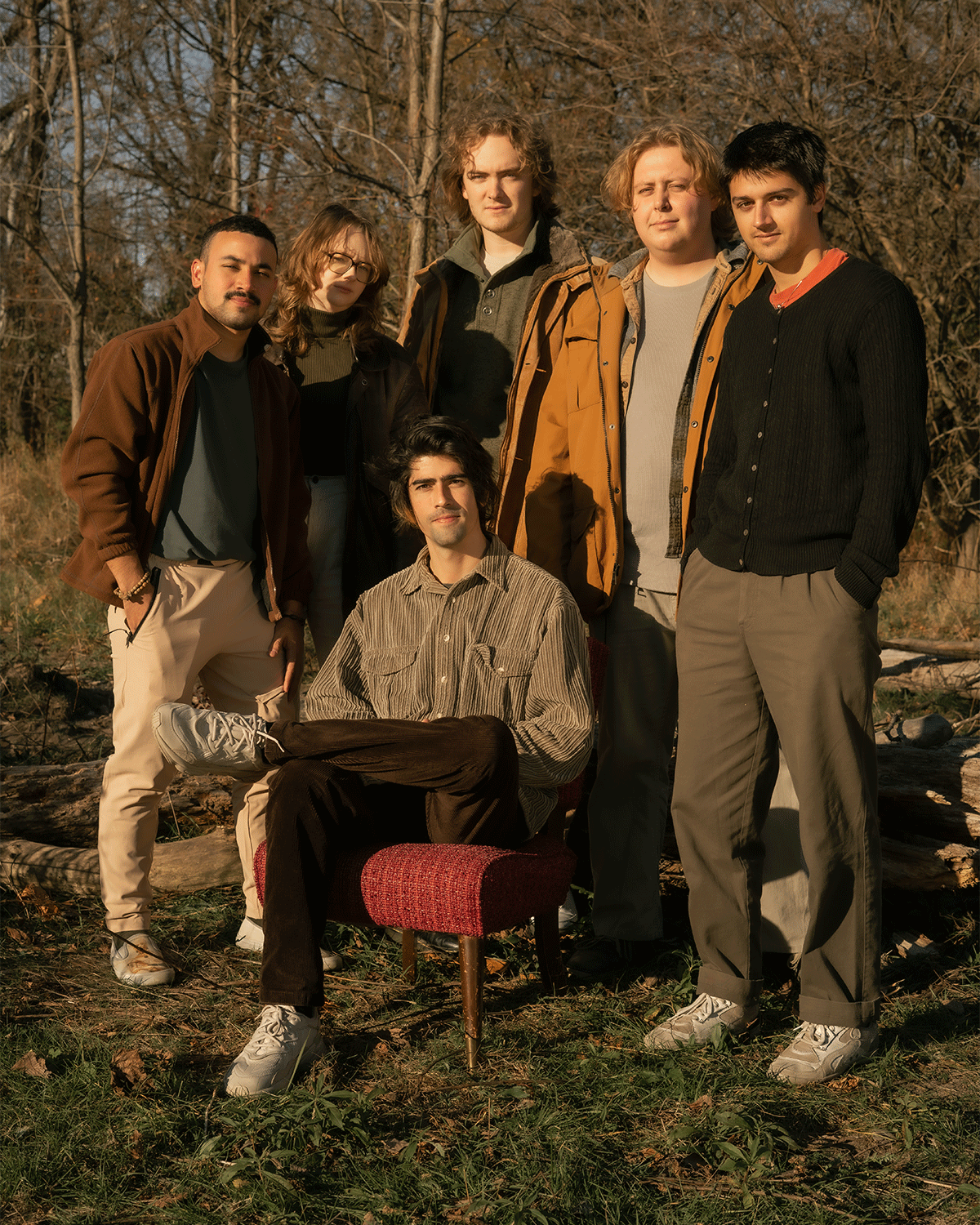 A band photographed together outdoors among autumn trees
