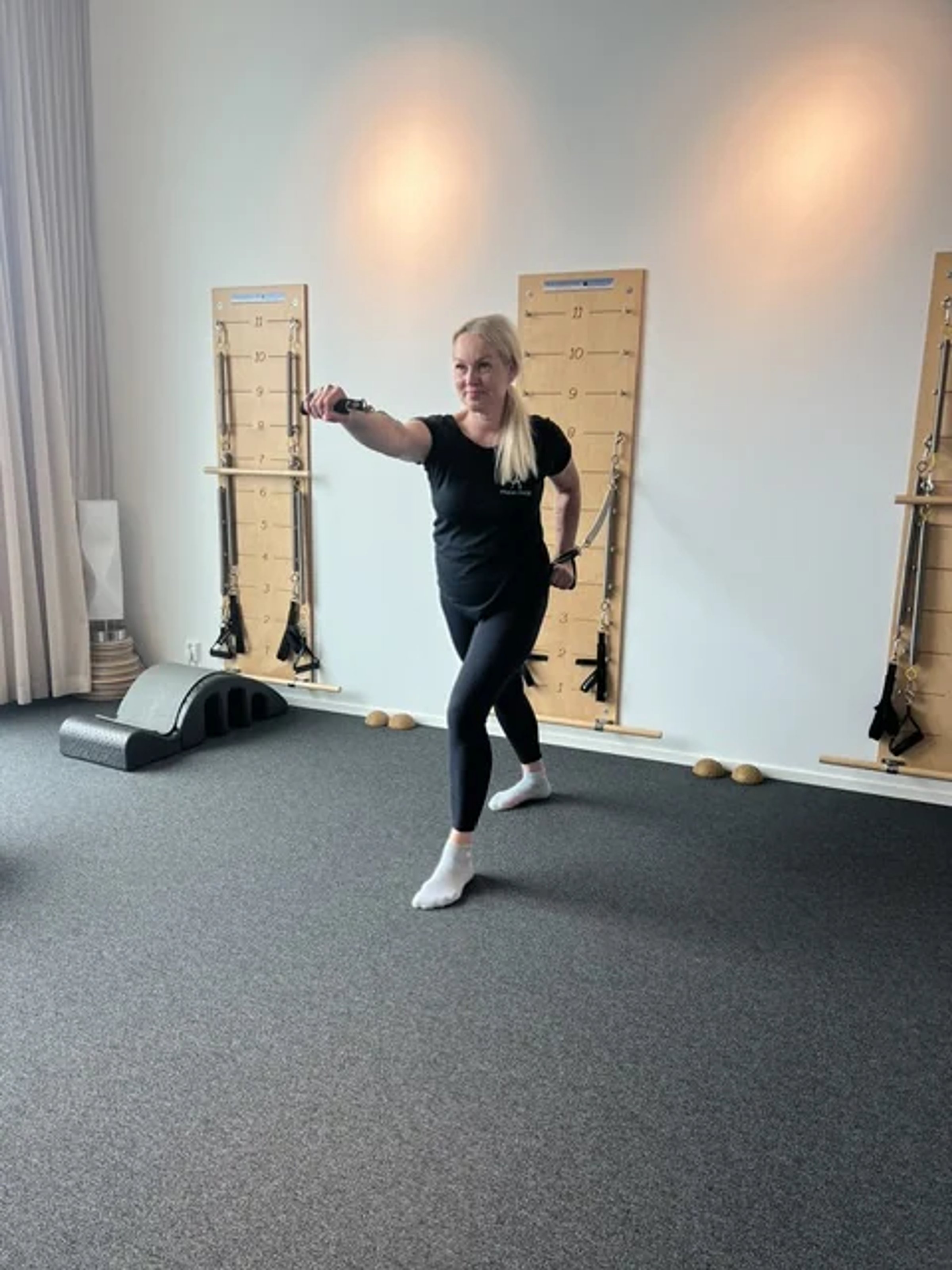 Ohjaaja tekee harjoitusta Springboard-seinälaitteen edessä Pilates Ateljéssa