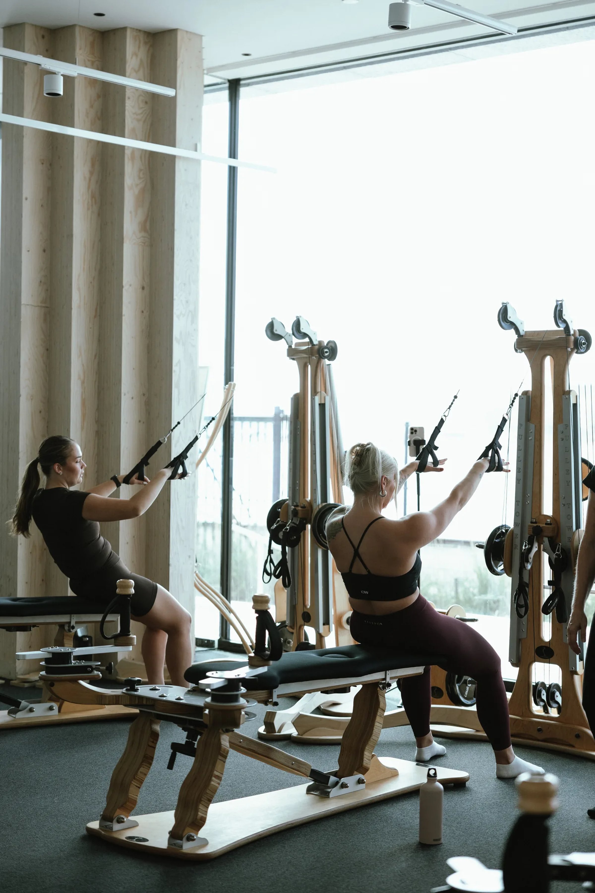 Kaksi harjoittelijaa GYROTONIC®-laitteilla ikkunan ääressä Pilates Ateljéssa Helsingissä