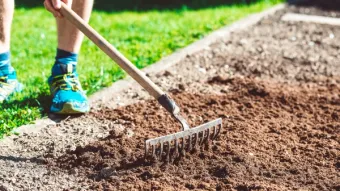 a person standing in fresh soil with a rake