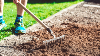 a person standing in fresh soil with a rake