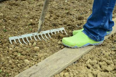 a person standing in fresh soil with a rake