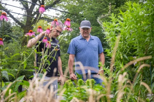 David and Howard standing in front of a wide-range, lively garden