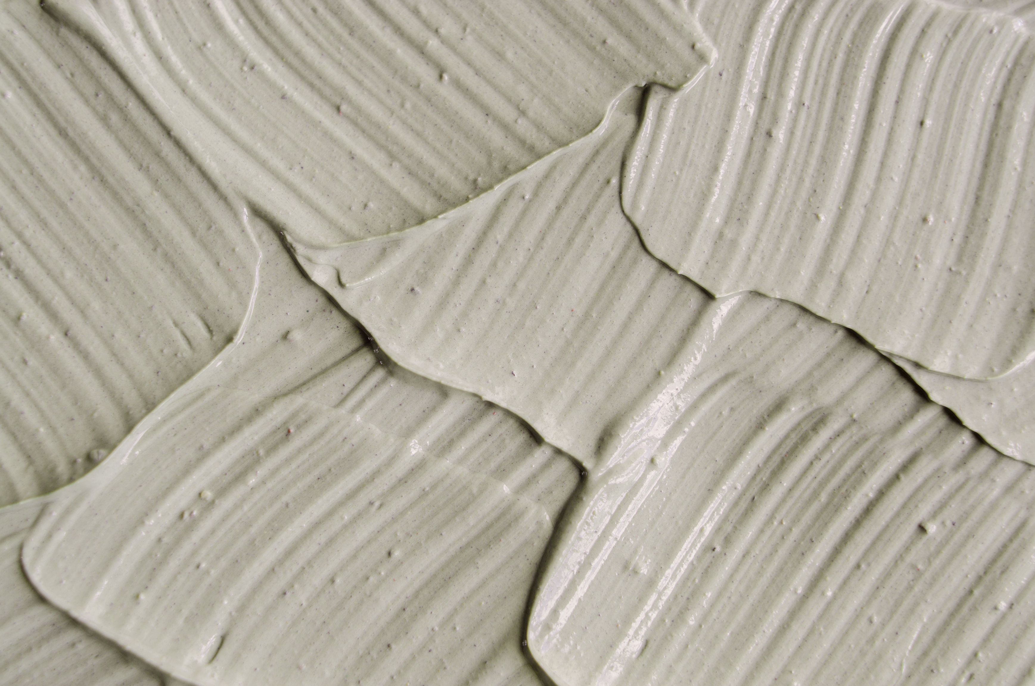 Gray cosmetic clay kaolin texture close up, selective focus. Abstract background with brush strokes. Gray cosmetic clay kaolin texture close up.