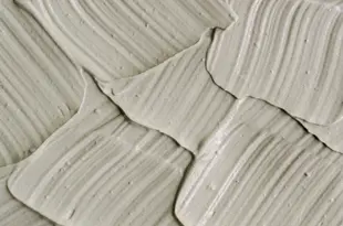 Gray cosmetic clay kaolin texture close up, selective focus. Abstract background with brush strokes. Gray cosmetic clay kaolin texture close up.