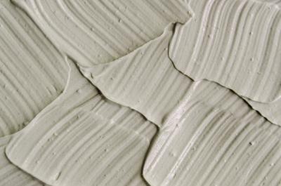 Gray cosmetic clay kaolin texture close up, selective focus. Abstract background with brush strokes. Gray cosmetic clay kaolin texture close up.